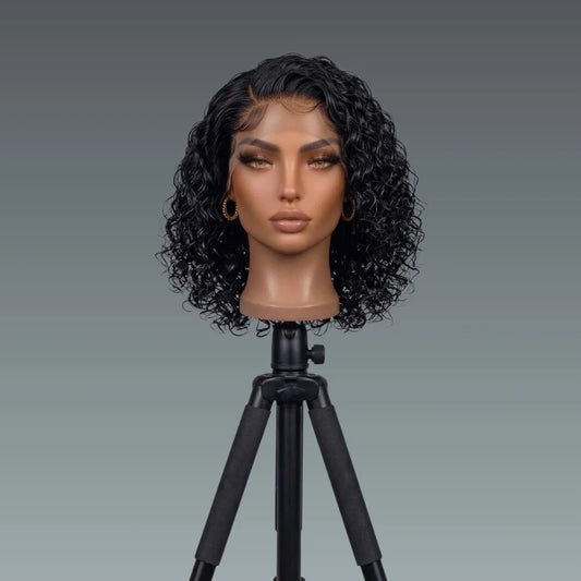 Mannequin head with curly black wig on a gray background