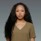 Woman with long, curly hair wearing a brown shirt against a gray background