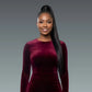 Woman wearing a burgundy velvet dress against a gray background