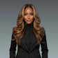 Woman with long, wavy hair wearing a black suit against a gray background