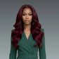 Woman with long burgundy hair wearing a green outfit against a gray background