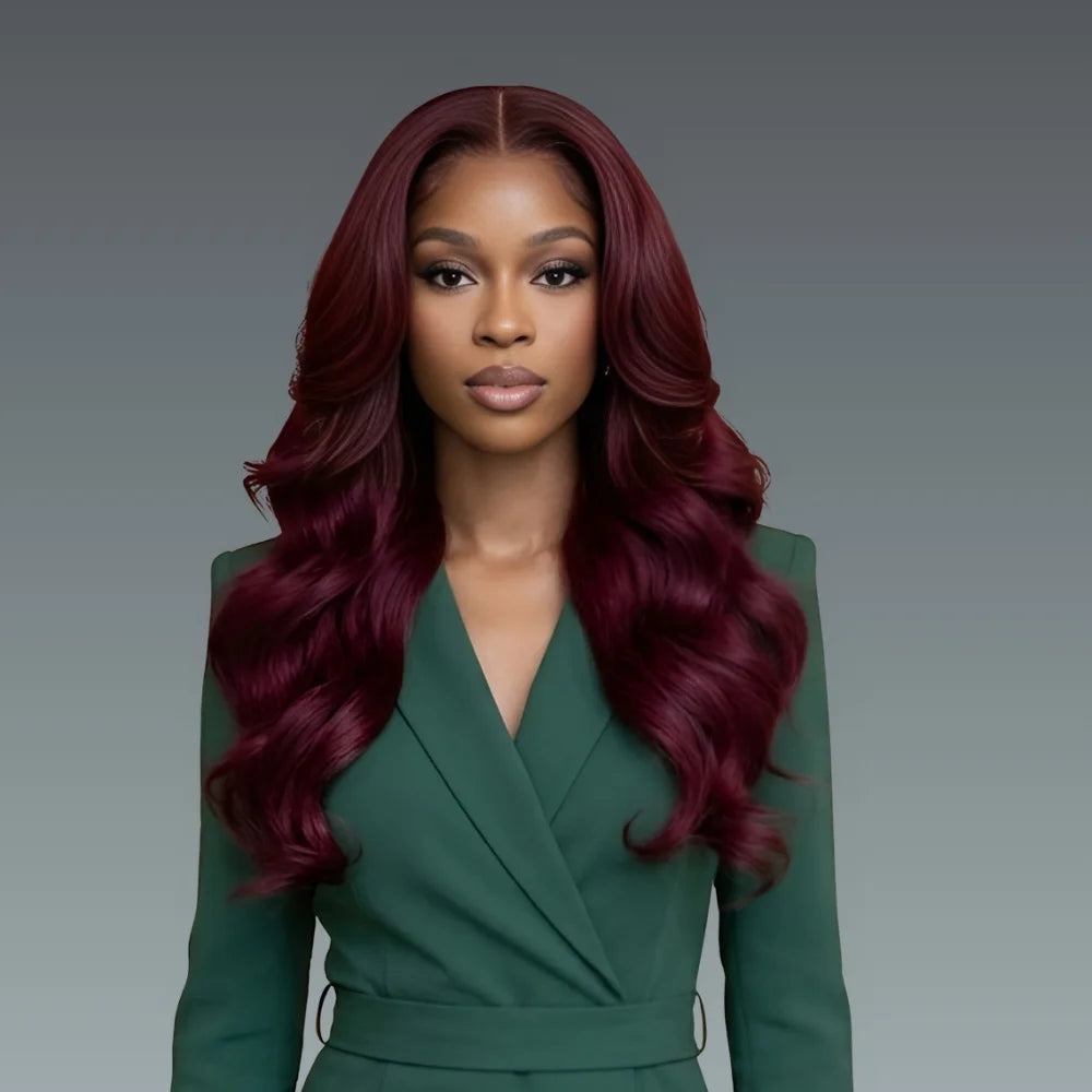 Woman with long burgundy hair wearing a green outfit against a gray background