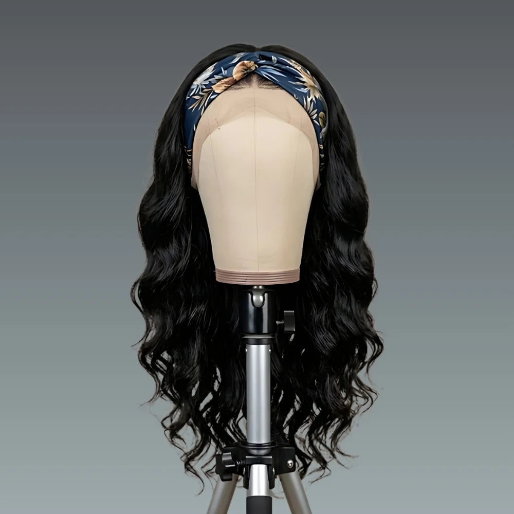 Black wavy wig on a mannequin head with a blue patterned headband against a gray background