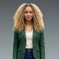 Woman wearing a green blazer over a white shirt with a blurred gray background