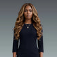 Woman with long wavy hair wearing a black top against a gray background
