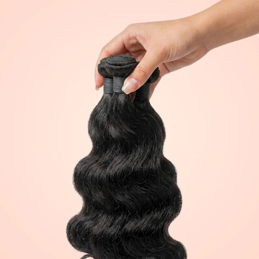 Hand holding a single Brazilian body wave hair bundle showing the double weft